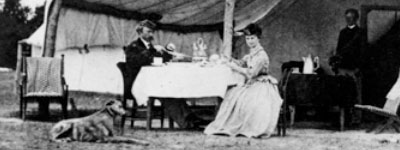 Black and white photo of a man and woman sitting at a table in a camp