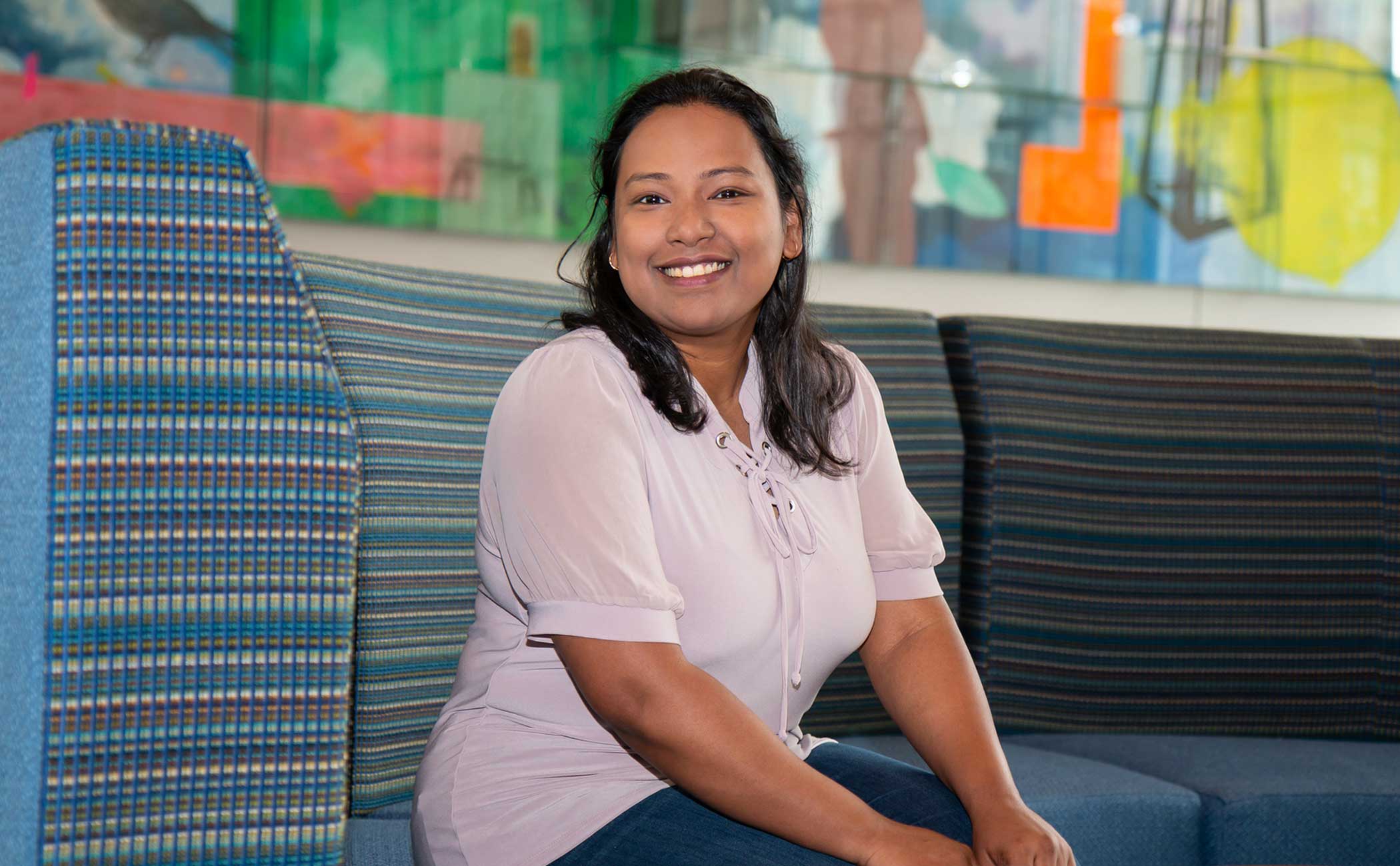 Saima Hasni sits on a blue chair in Carolyn Pope Edwards Hall