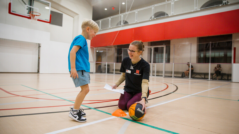 Hailey Klein, a graduate student in speech-language pathology, works with a young child during a session of the Itty Bitty Sports program