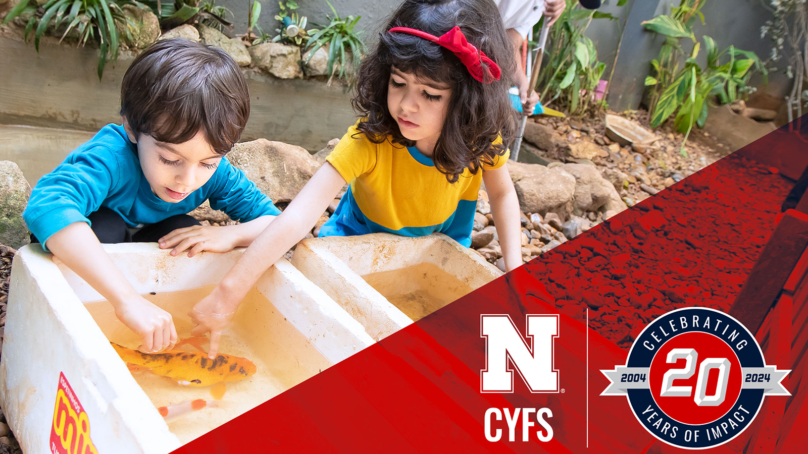 two children play with water, CYFS logo and CYFS 20th anniversary logo in bottom right