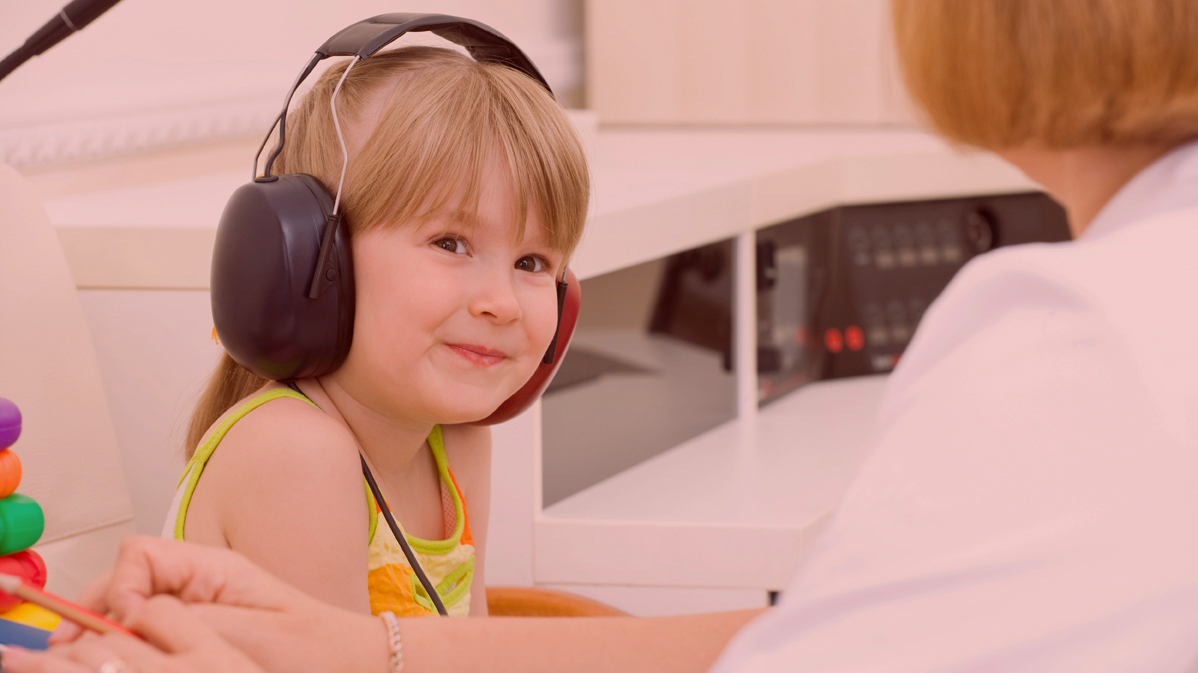 young girl smiles during a hearing test