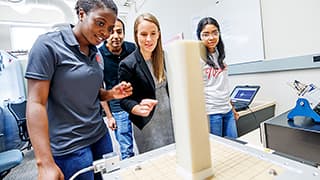 A civil engineering professor and her three students watch as a shake table jolts a column and its base.